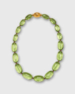 Load image into Gallery viewer, A beaded necklace featuring translucent light green oval beads separated by tiny red spacers, with a polished gold oval clasp at the top, displayed on a light gray background.