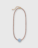 Load image into Gallery viewer, A delicate necklace featuring a thin reddish brown beaded cord, a gold-tone extender chain, and a single smooth, light blue bead at the center, displayed on a neutral light gray background.