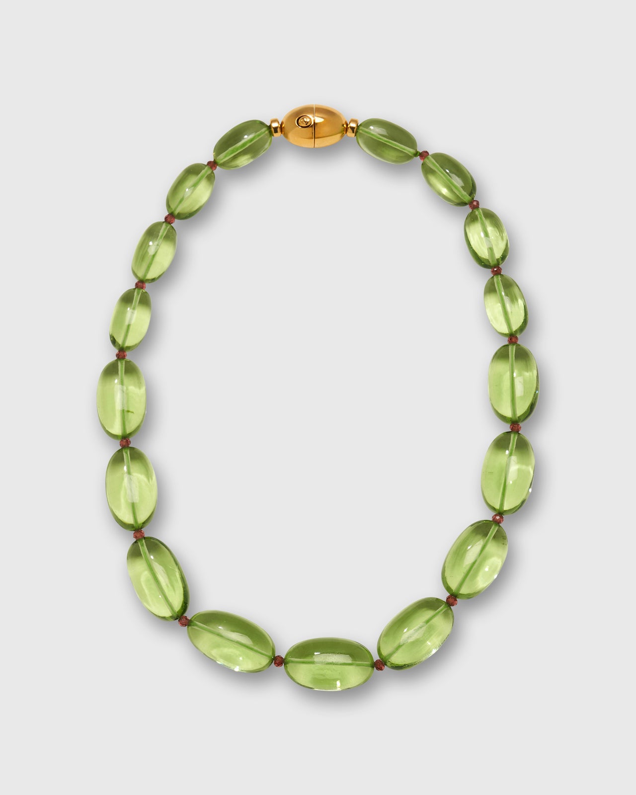 A beaded necklace featuring translucent light green oval beads separated by tiny red spacers, with a polished gold oval clasp at the top, displayed on a light gray background.
